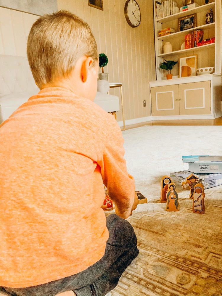 Child playing with World Charity Set figurines by Puzzle Planet: Saint Blaise, Mother Teresa, Padre Pio. Wooden Saints Figures.