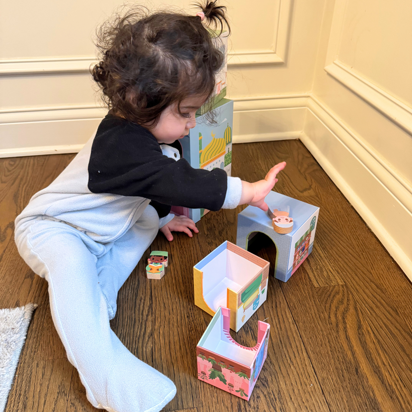 Child playing with Puzzle Planet's stacking houses toy set. Fine motor skills development with colorful toy blocks.