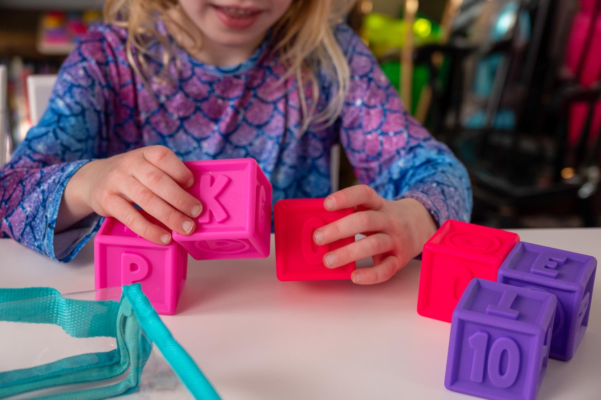 Toddler playing with SQUEEZE & STACK letter and number blocks from Puzzle Planet, improving motor skills. Colorful toy.
