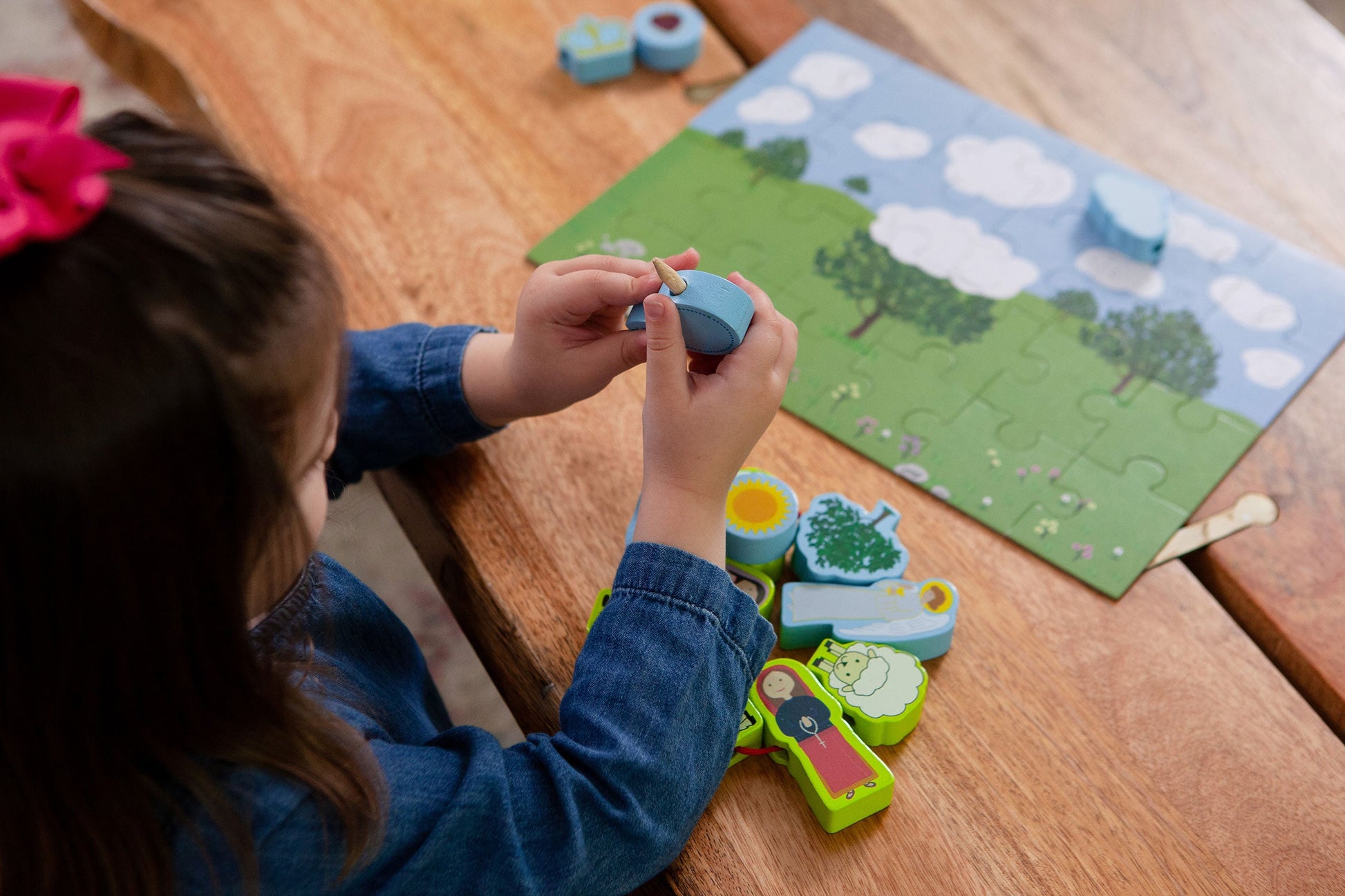 Child plays FATIMA LACING SET wooden toy from Puzzle Planet. Puzzle and wooden figures of Our Lady of Fatima are visible.