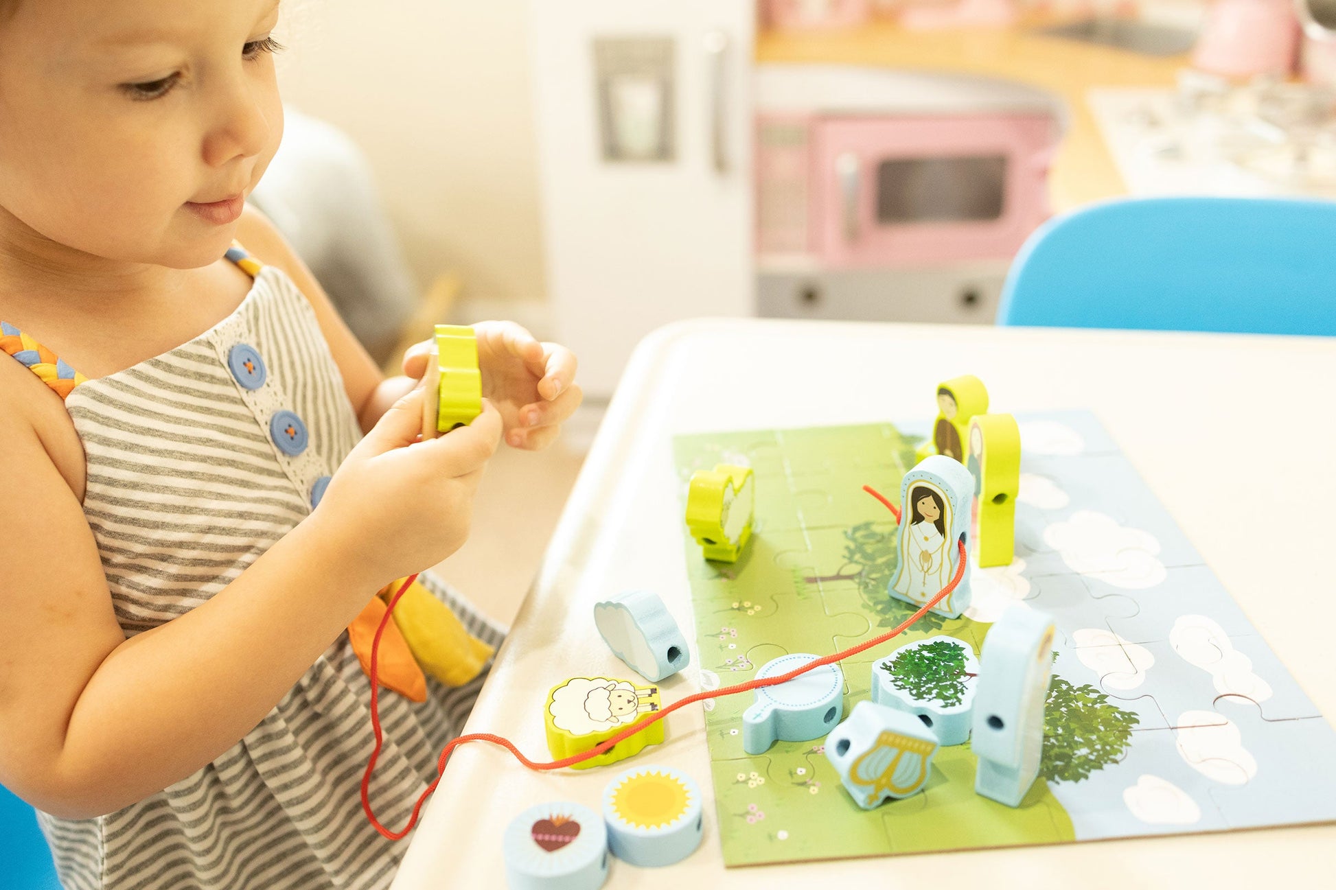 Child playing Our Lady of Fatima wooden lacing set. Religious toy for Catholic kids improving fine motor skills.