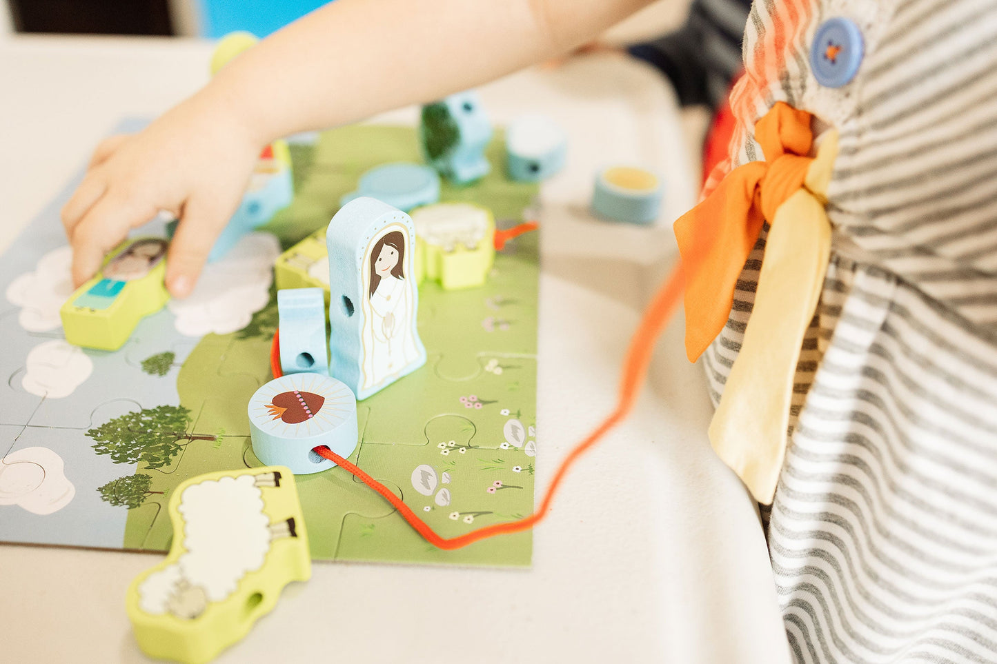 Fatima Lacing Set: Child playing with wooden Fatima puzzle, developing fine motor skills. Catholic toy.