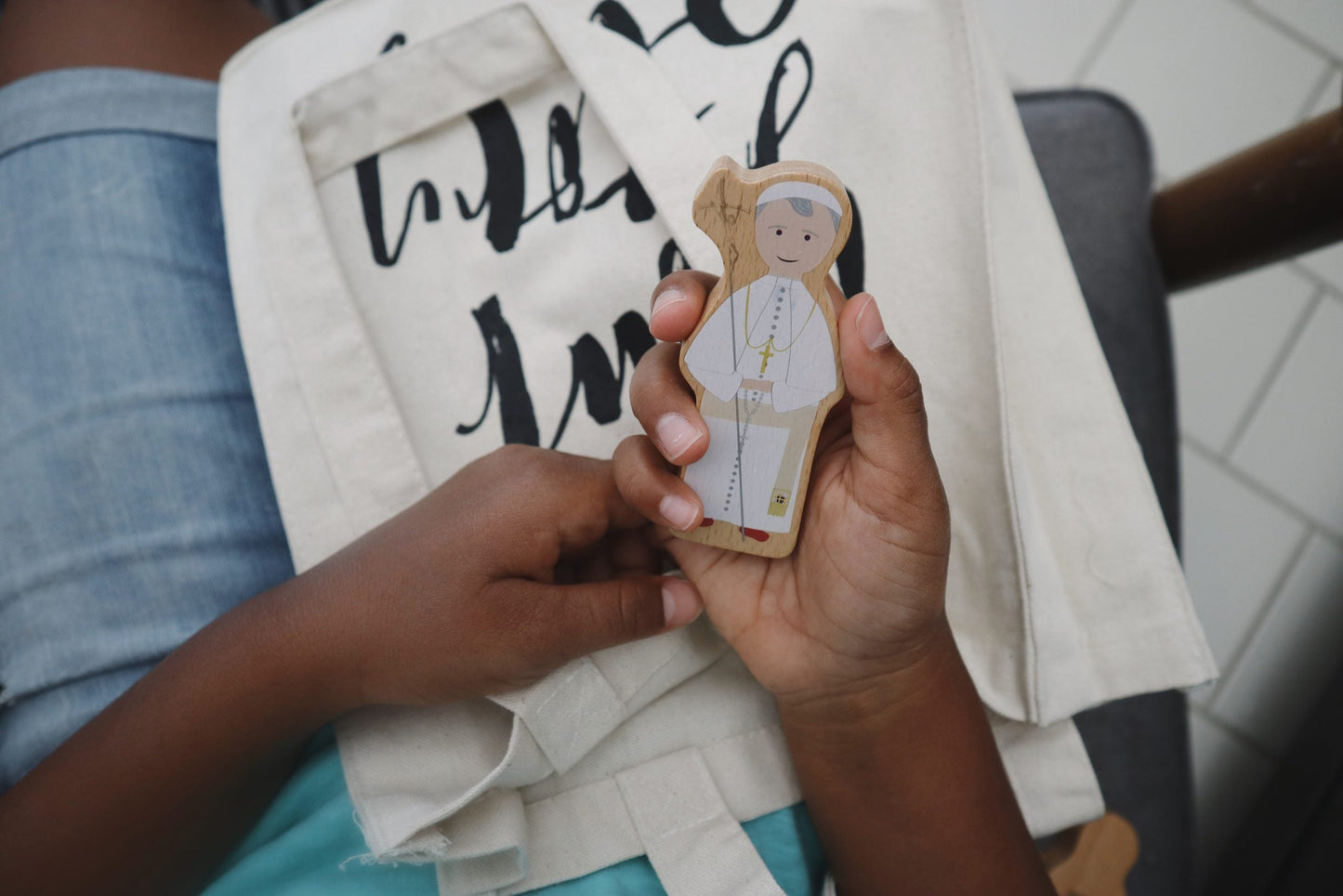 Child holding Saint John Paul II wooden toy from the Totus Tuus set by Puzzle Planet.