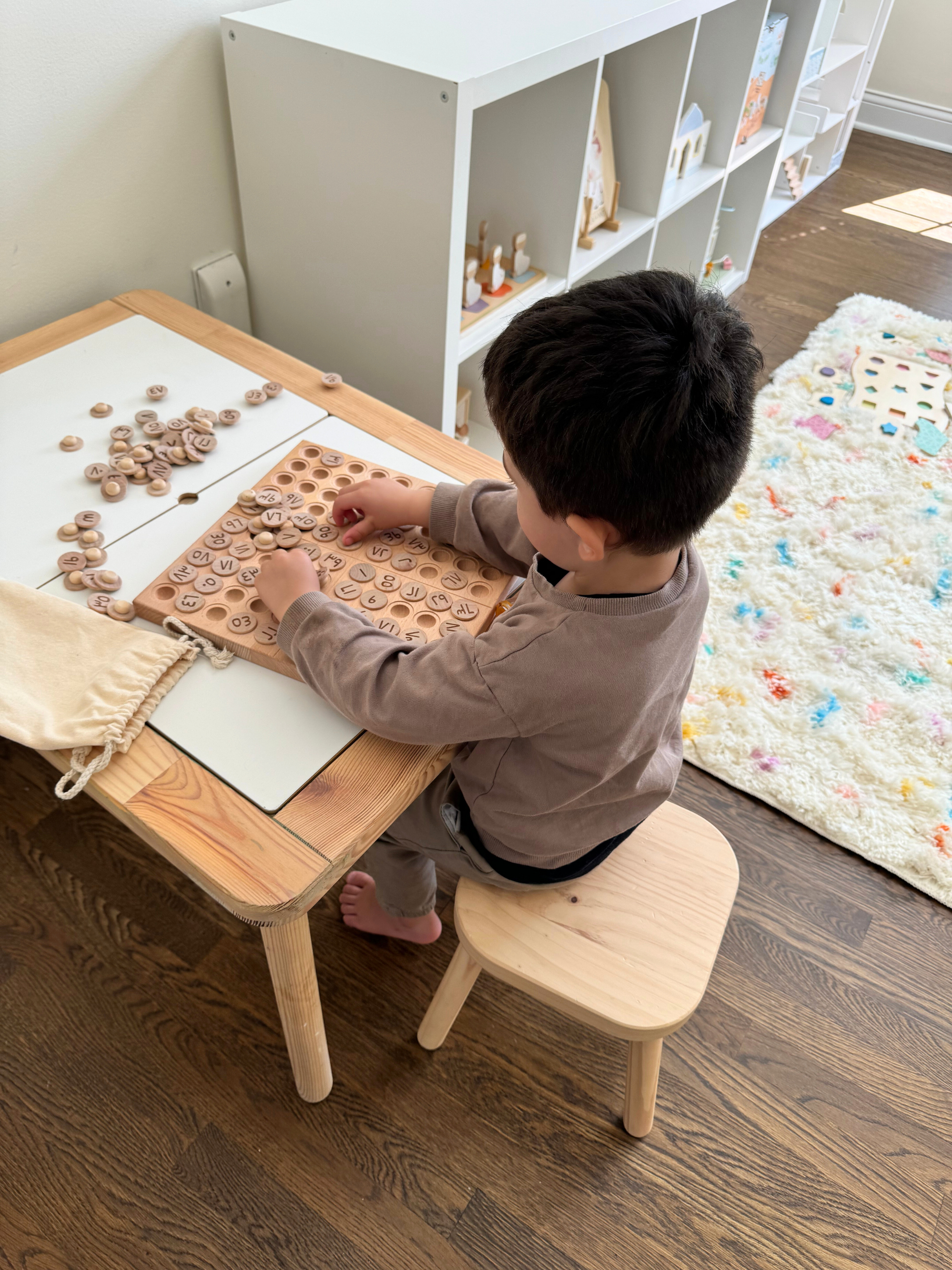 Child playing with Montessori Hundred Board: Arabic Names of Allah learning and counting game.