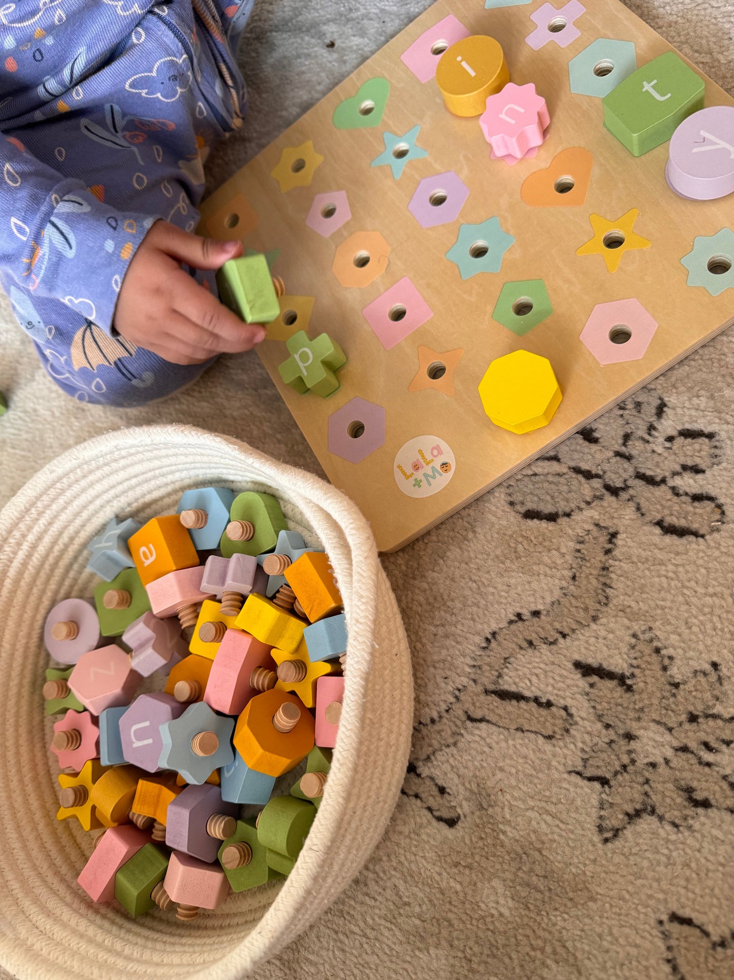 Child playing with Puzzle Planet English Arabic Alphabet Bolt & Board wooden toy, basket & board, Lola + Me branding.