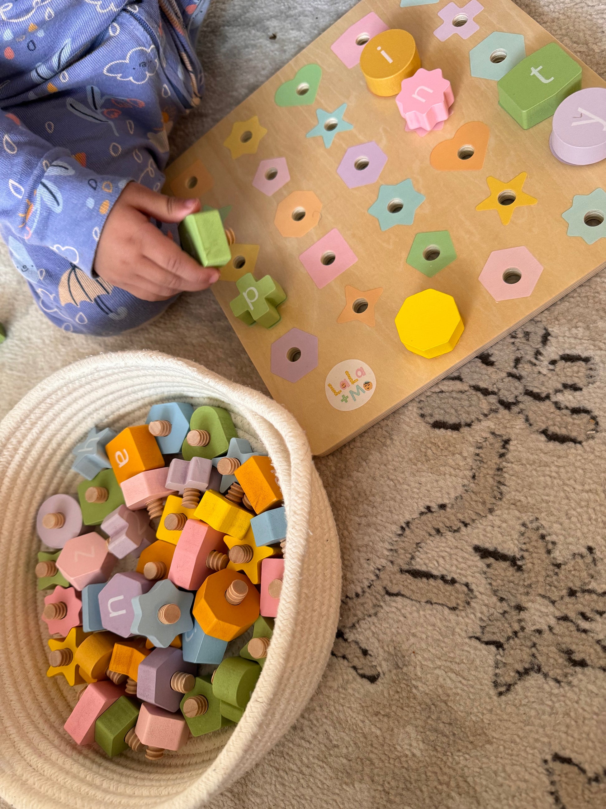Child playing with Puzzle Planet English Arabic Alphabet Bolt & Board wooden toy, basket & board, Lola + Me branding.